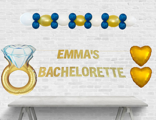 Decorative setup for Emma's bachelorette party with balloons and text on a white brick wall.